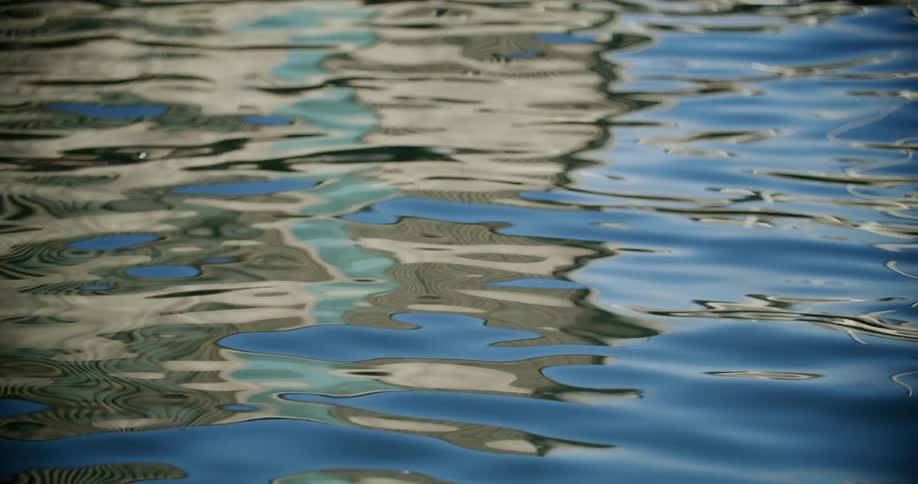 A water surface reflecting the sky and buildings creating a mesmerizing pattern of blues grays and whites