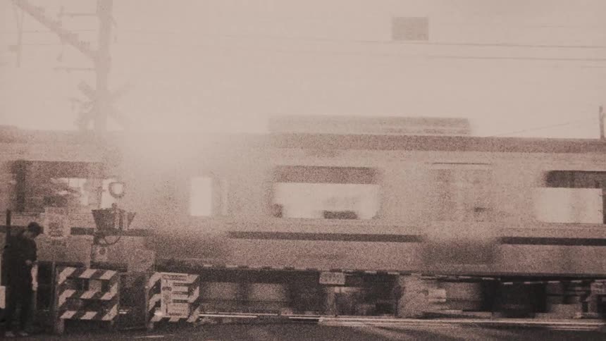 A train in motion blurred due to its speed passing through a railroad crossing with its gates lowered