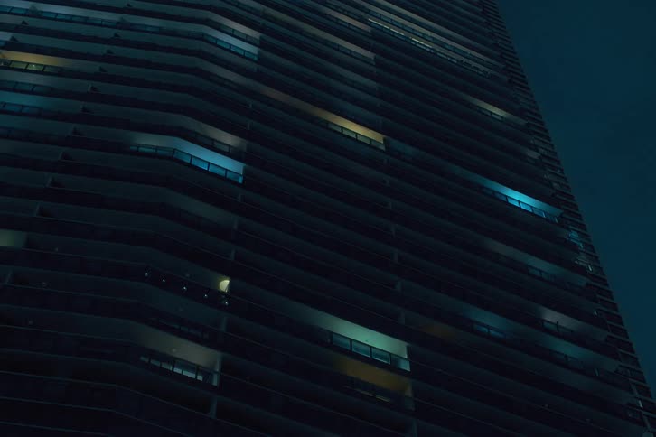 View up a modern urban building with lights blinking at night