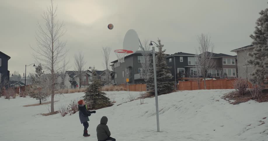 A footage of children playing basketball in the snow