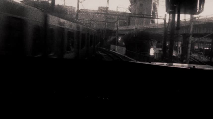 Person at the end of a subway train stands silhouetted against the window while another train passes in the opposite direction