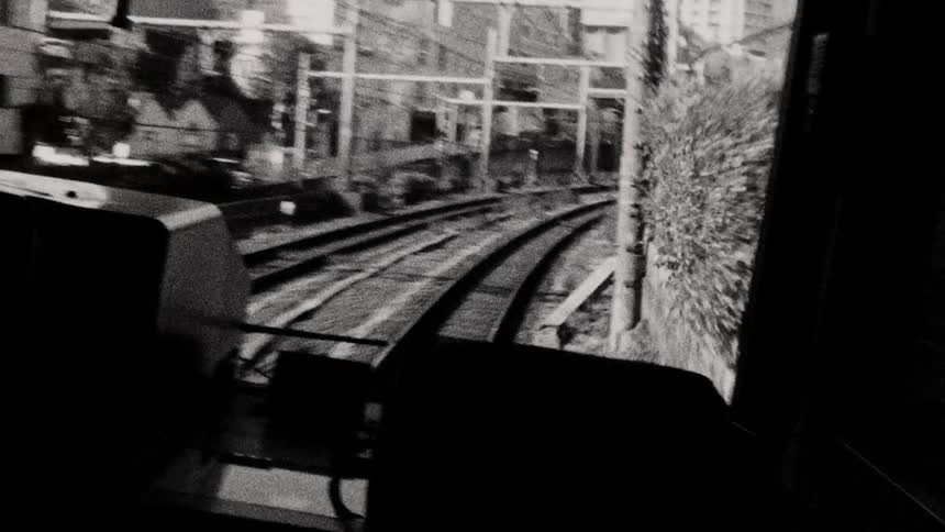 A view from the back of a train moving along curved tracks through an urban area