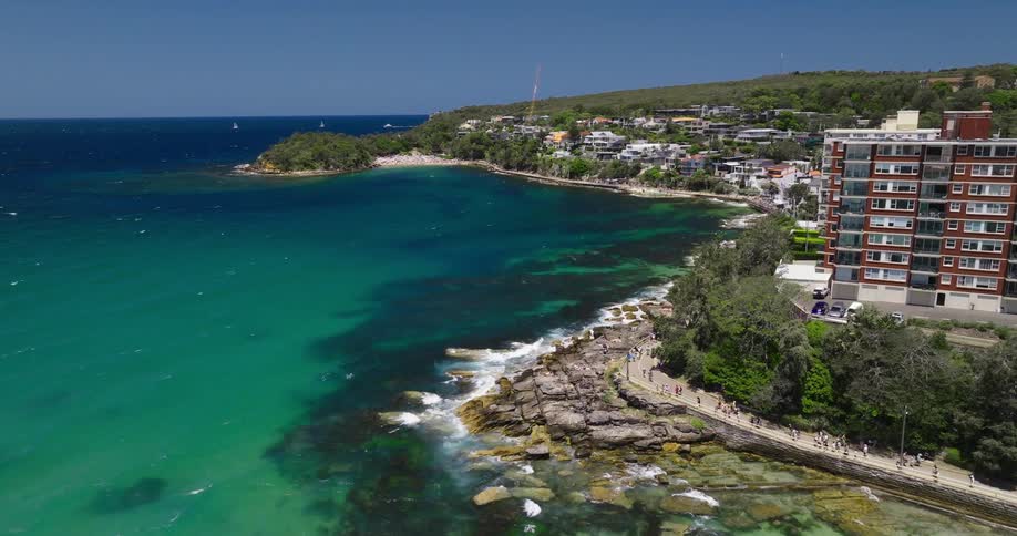 Tourists walk along a road in a coastal destination location on a sunny day