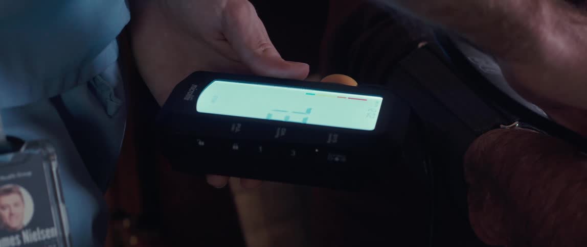 A person holding a handheld blood pressure monitor on another persons arm