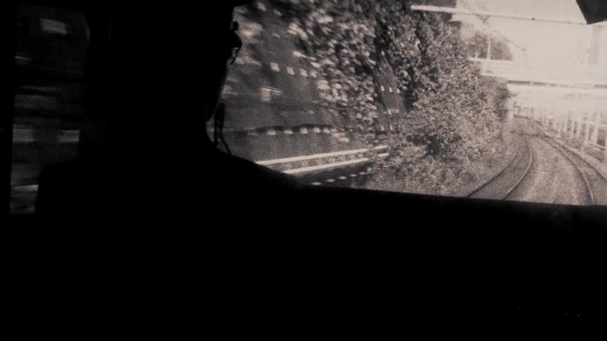 A silhouette of a person inside a train with a view of train tracks curving
