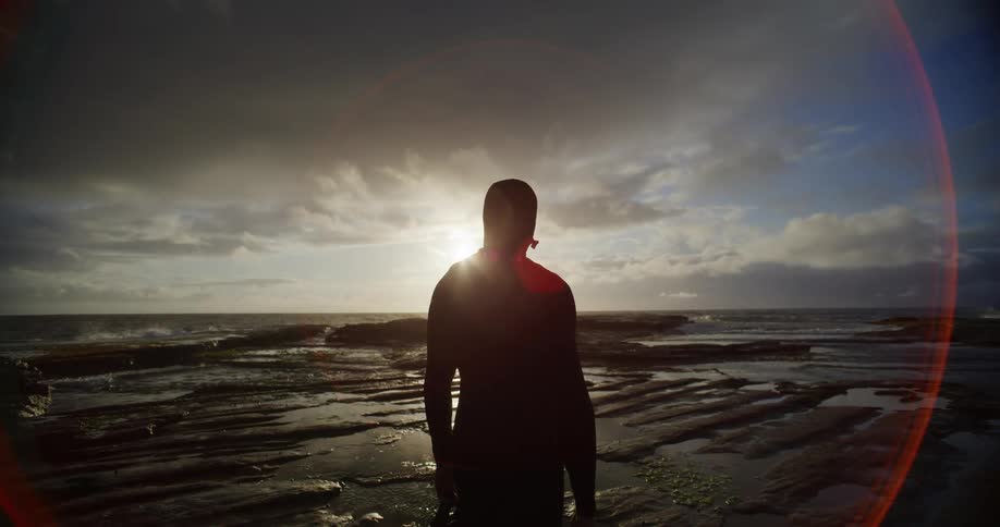 Silhouette of a person in a natural area with the sun reflecting on the horizon