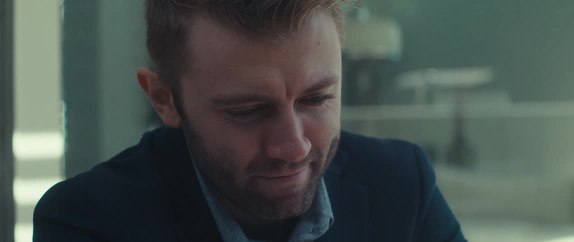 Blond man in blazer making signs and talking