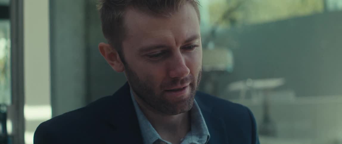 Blond man in blazer in outdoor area making body gesture