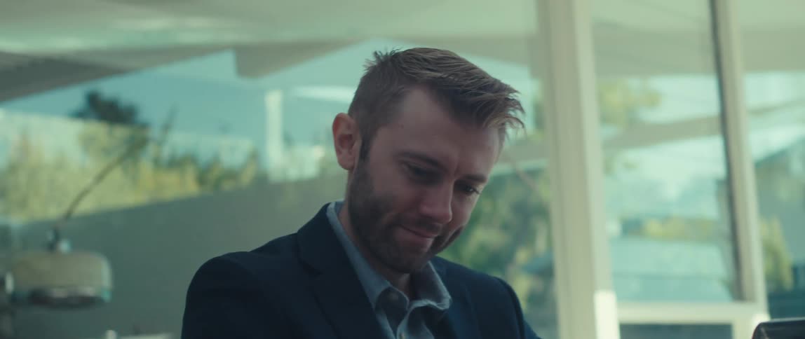 Man ending a call on smartphone and making a negative sign while sitting in front of a laptop
