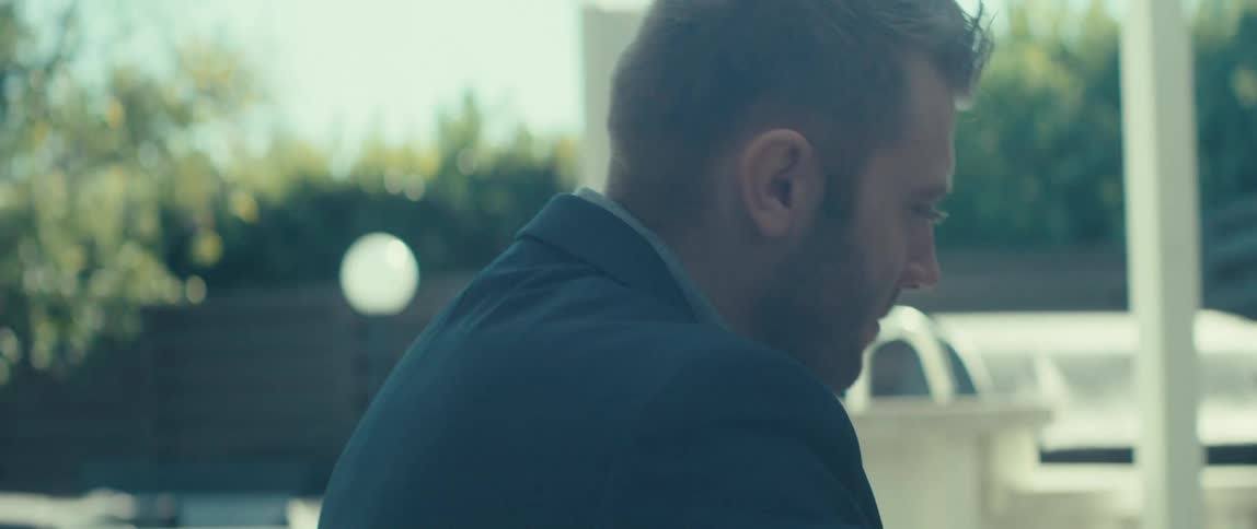 Man in dark blue blazer sitting in outdoor area