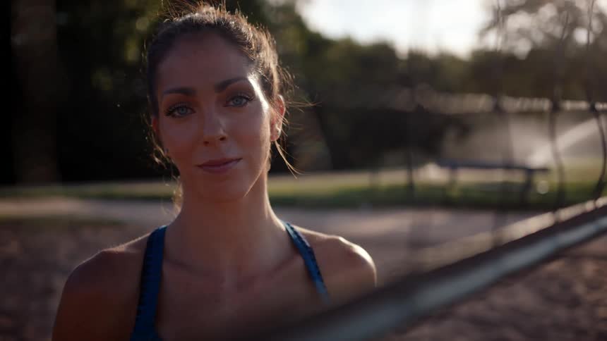 Portrait of a woman holding a ball on a sand volleyball court