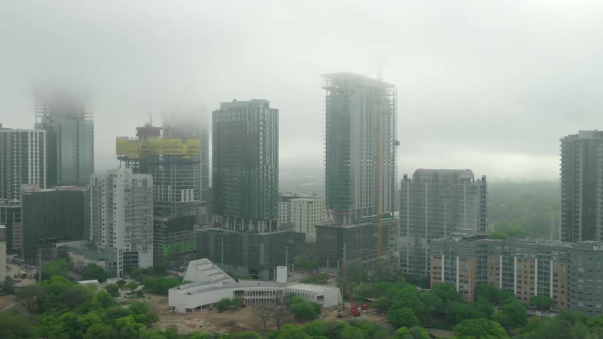 An aerial clip of high rise buildings in a city covered with mist