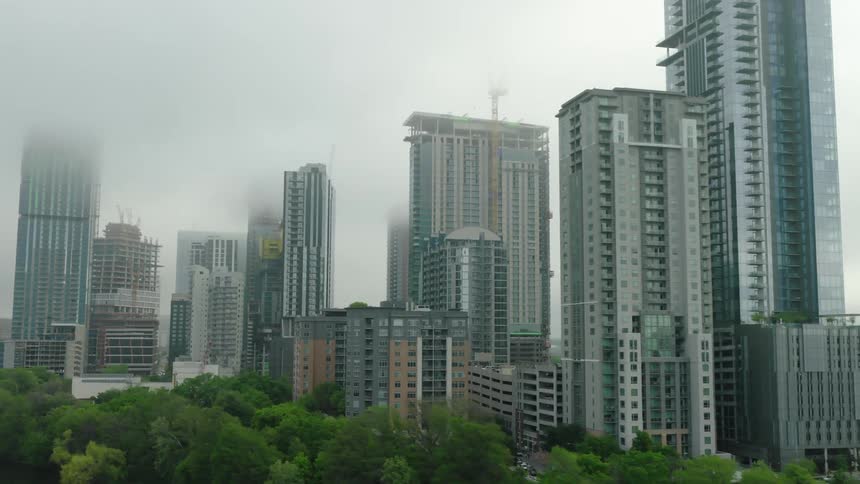 The center of a city with some large buildings and a dancing fog hovering over them