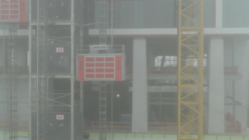 Aerial view of a building under construction with a load rising on a foggy day