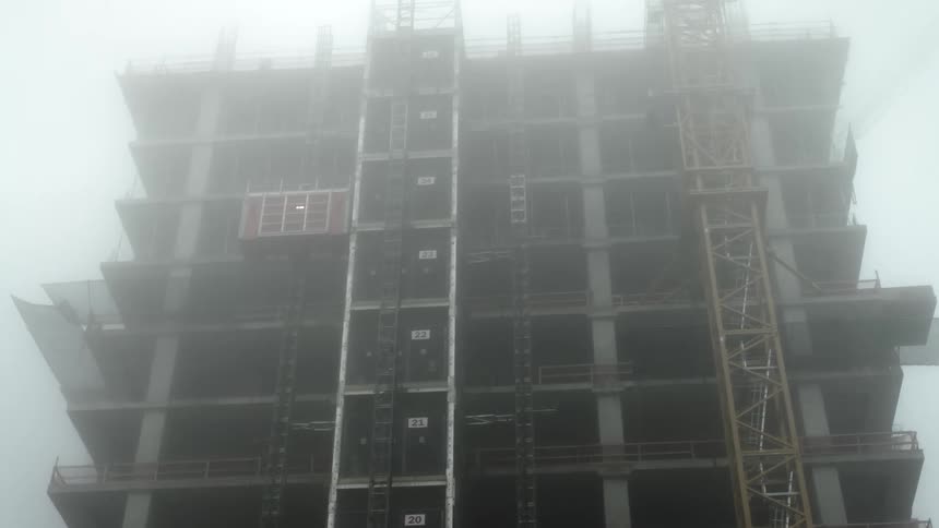 A multistory building under construction enveloped in fog