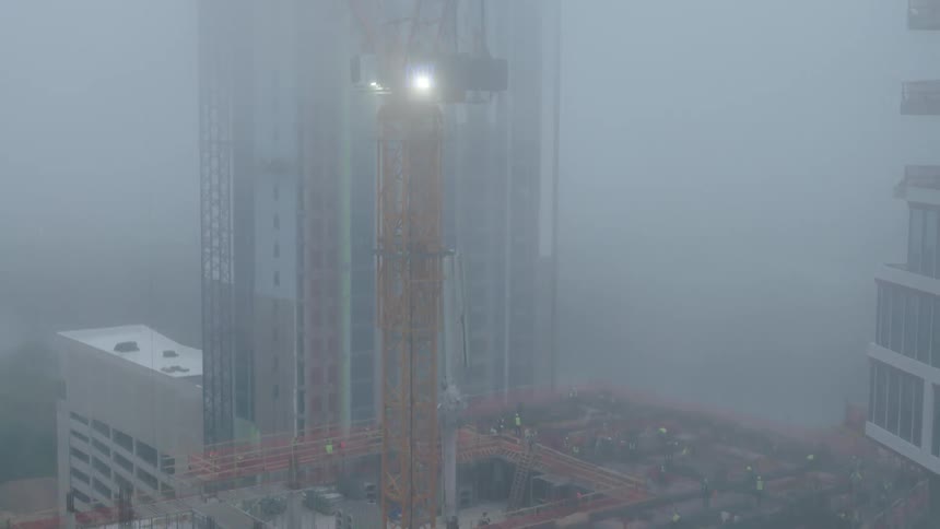 Aerial view of workers on a skyscraper on a foggy day