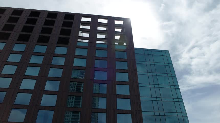 Modern building with a dark facade large windows and geometric design contrasting with the cloudy sky in the background