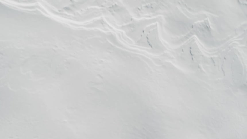 A snow covered surface with visible tire tracks and a delicate dusting of fresh powder