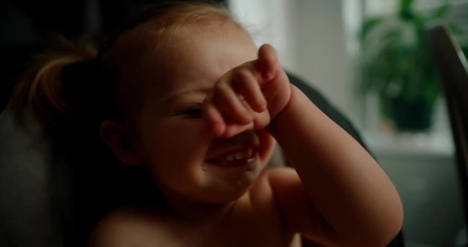 Portrait of a little girl playing and a hand with a spoon applying cream on her nose