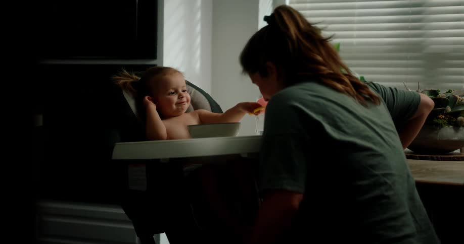 Little girl feeding baby food to her mother while playing
