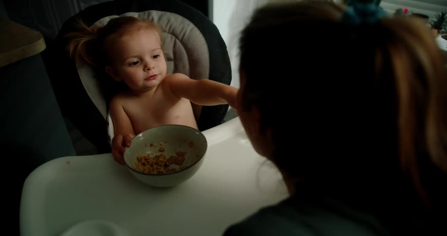 Little girl sitting offering a spoonful of rice to her mother