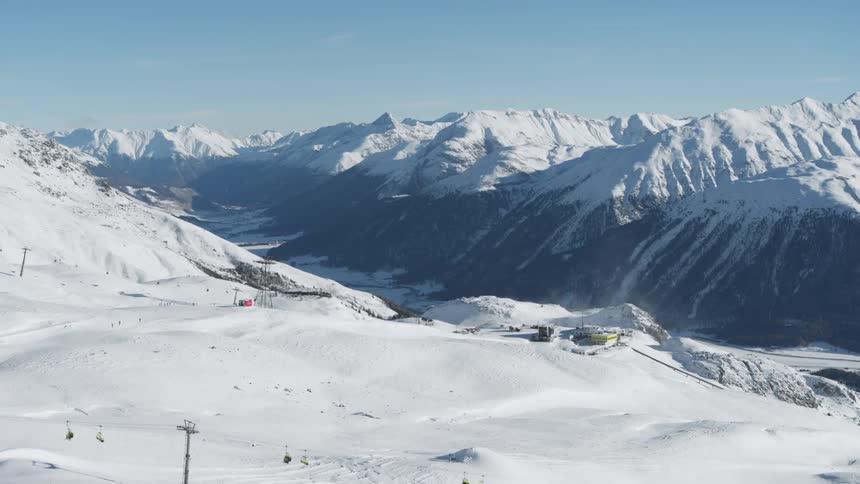 Aerial view of a snowcovered ski resort with several ski lifts and slopes winding through the mountain landscape