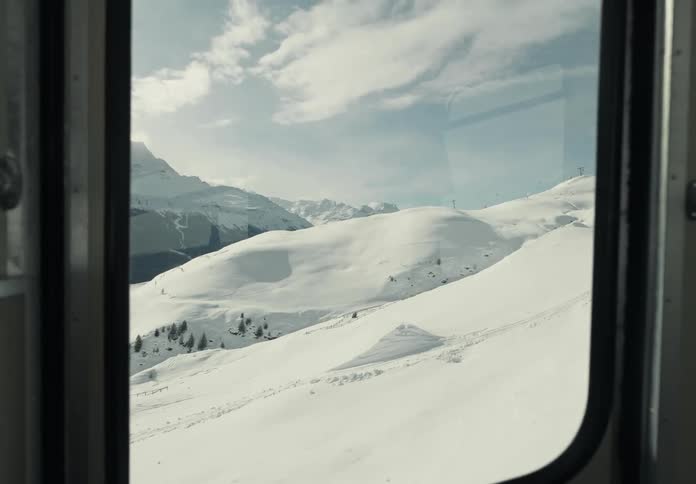 Interior view of a cable car moving up a snowy mountain on a cloudy day