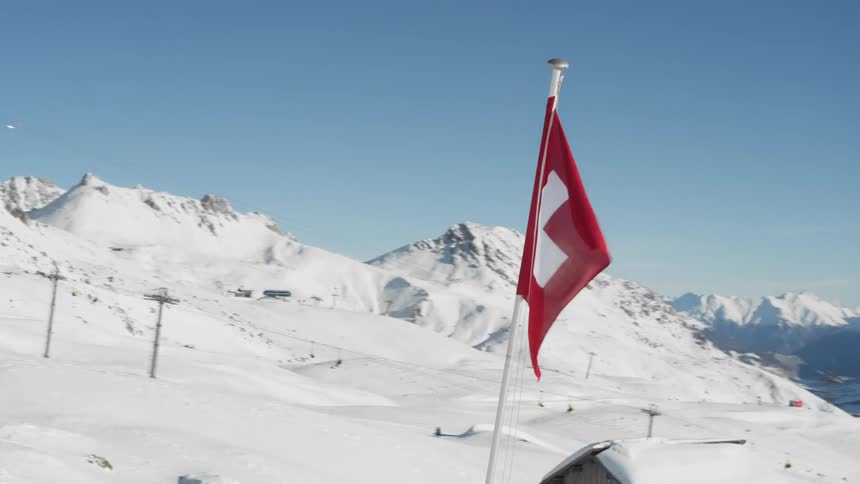 Flag of switzerland against a backdrop of snowy mountains