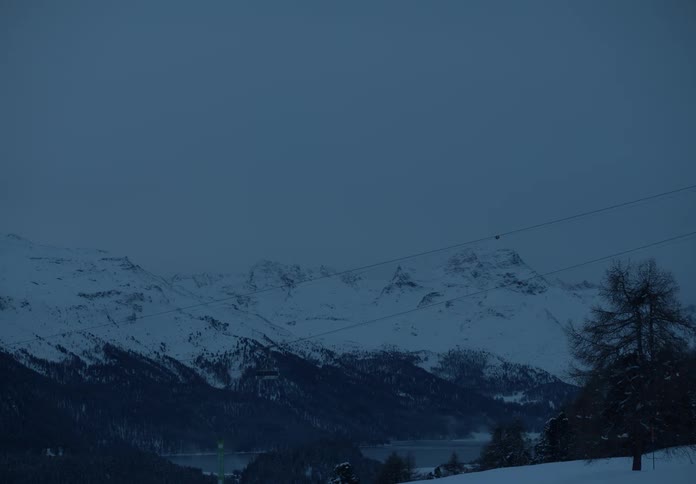 Landscape of cable cars in the foreground and a lake and snowy mountains in the background