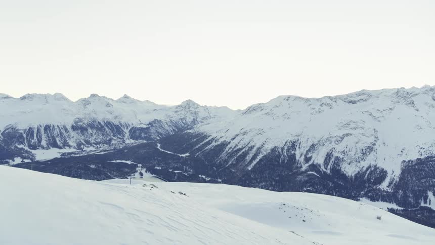 Aerial view of a snowy mountain valley and in the background cable cars in operation