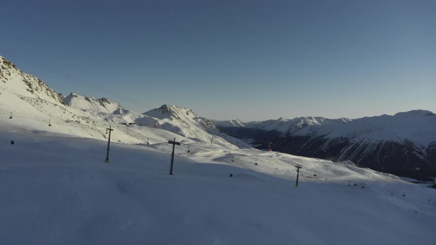 Aerial view of people skiing and others on ski lifts on a snowy mountain