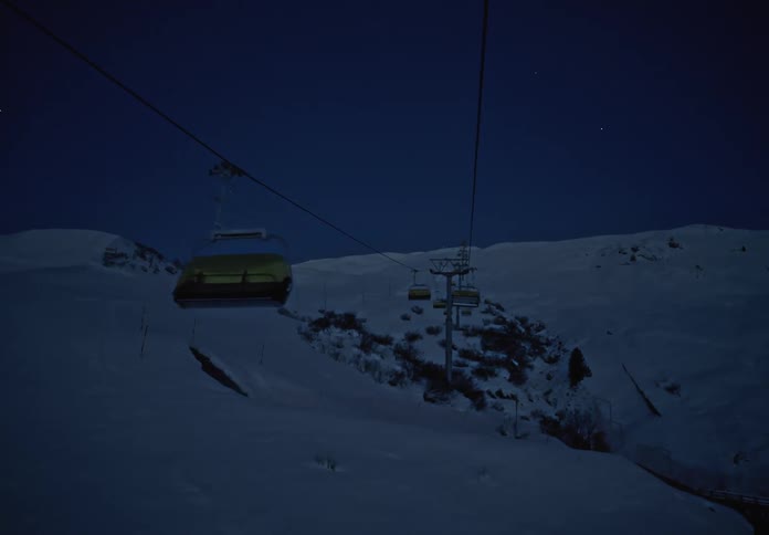 Empty gondolas of a ski life move along the cable over snowy mountains