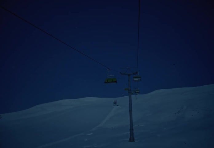 Point of view of cable cars moving up a snowy mountain at night