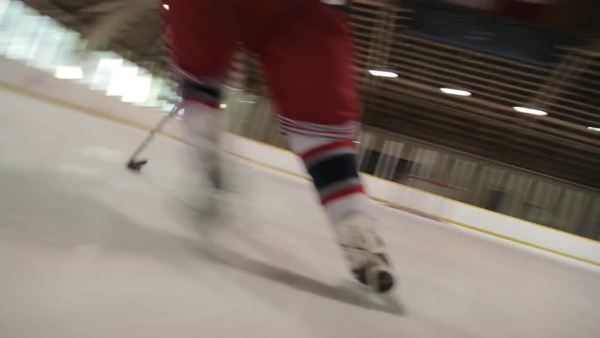 Person driving a puck to a goal on an ice rink
