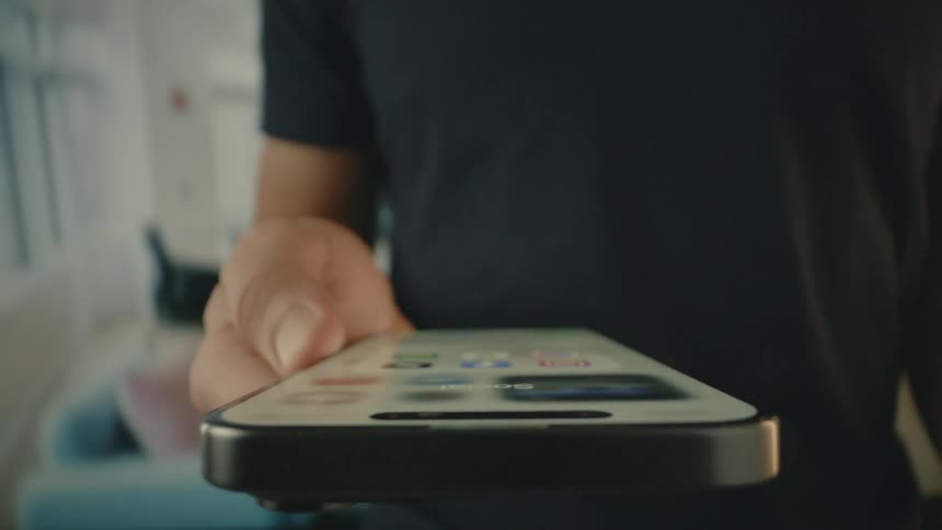 Person holds a smartphone while standing in his living room