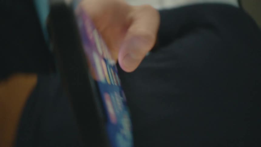 A man looks at an options menu on his smartphone then scrolls