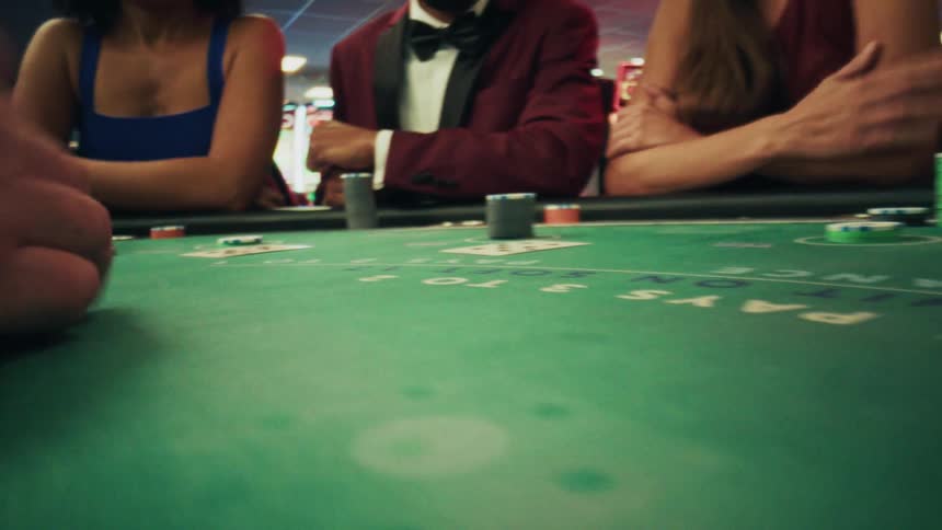 Pair of hands dealing poker cards on a table with players