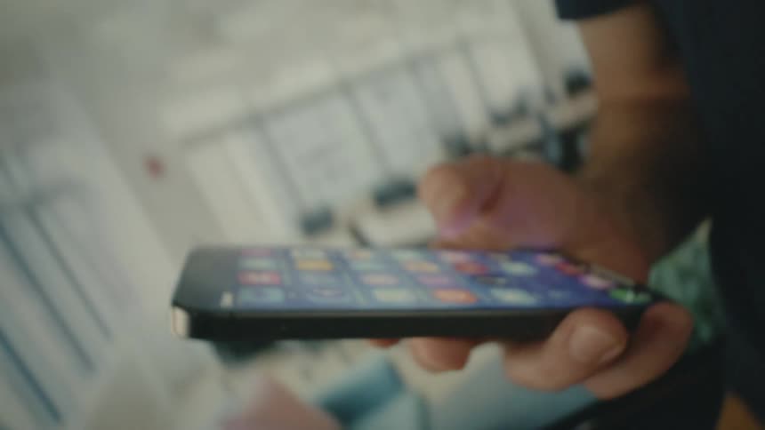 Spinning footage of a person scrolling through a smartphone in a brightly lit office
