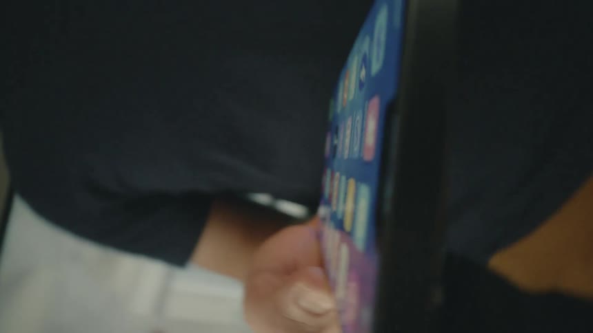A man in a black t shirt holding an iphone in his hand