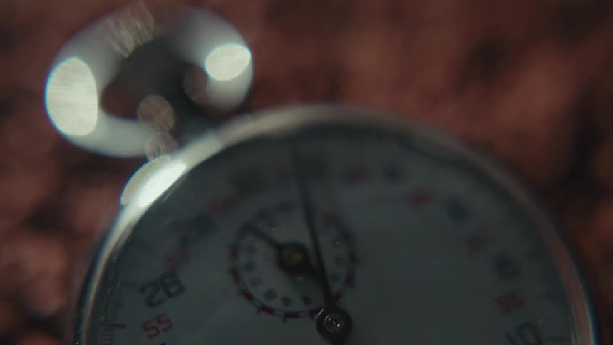 A close up shot of a stop watch with the lens slightly out of focus moves from a clear view of the dial to a blurry one