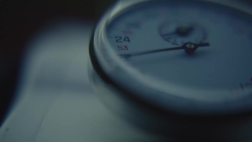 A hand on a stopwatch spins past numbers
