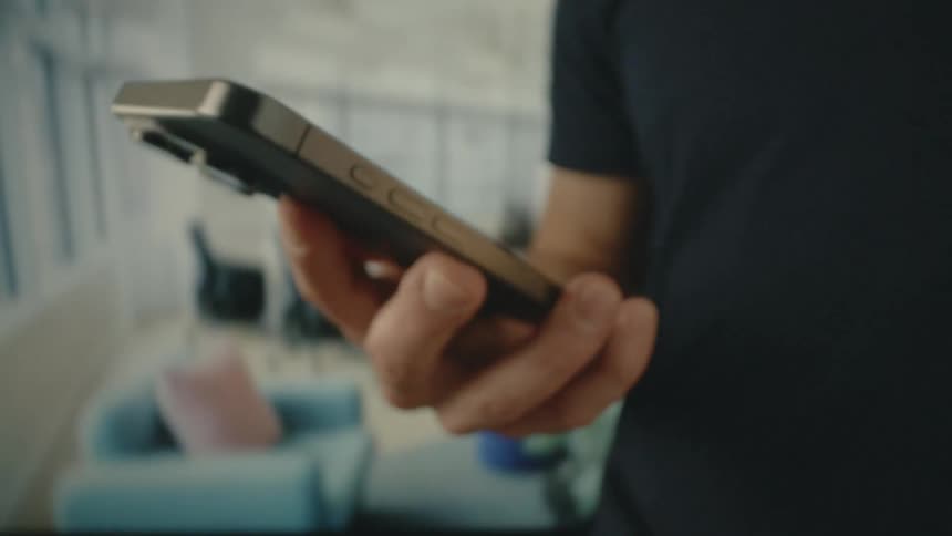 A man wearing a black t shirt holding an iphone in his hand