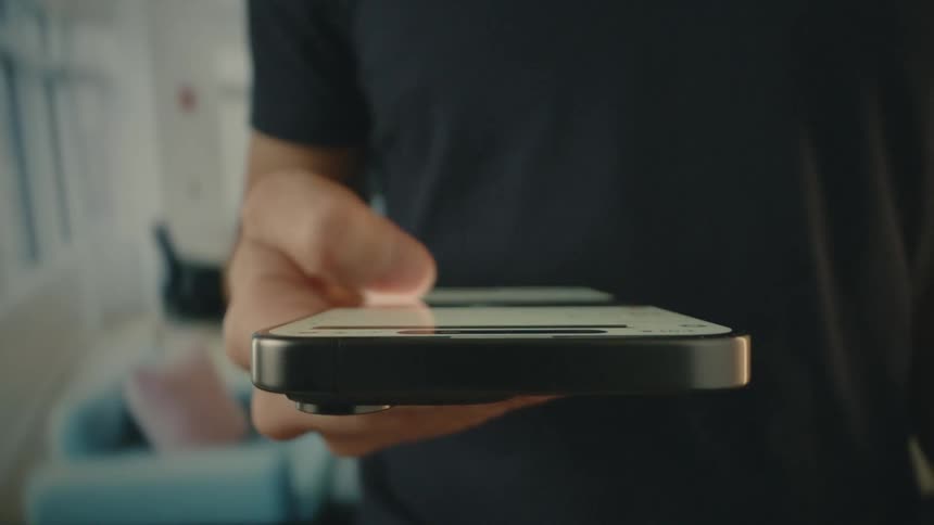 A man in a dark shirt scrolls on his smartphone