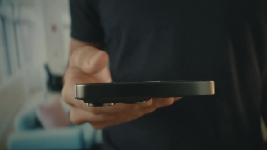 A man wearing a black t shirt holding an iphone in his hand
