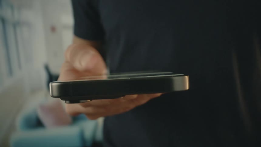 A man wearing a black tshirt uses an iphone