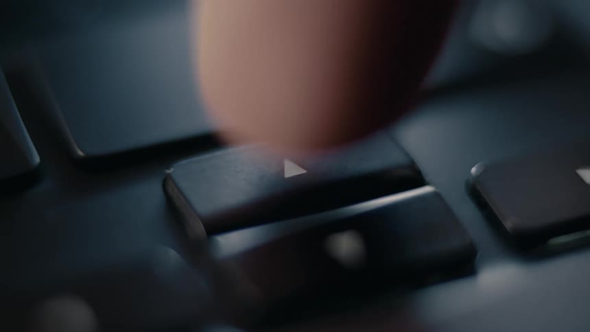 A close up slightly blurry shot shows a finger pressing the up and down key on a black keyboard
