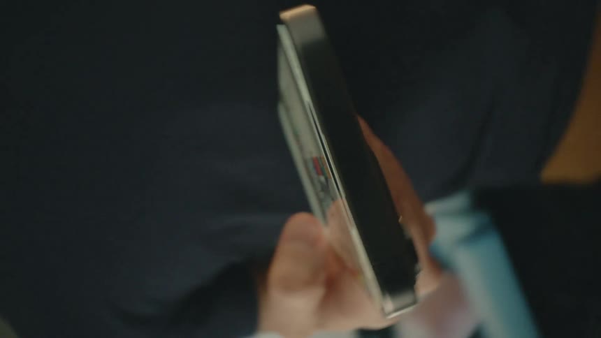 A man holds his phone with one hand and uses his thumb to move the screen