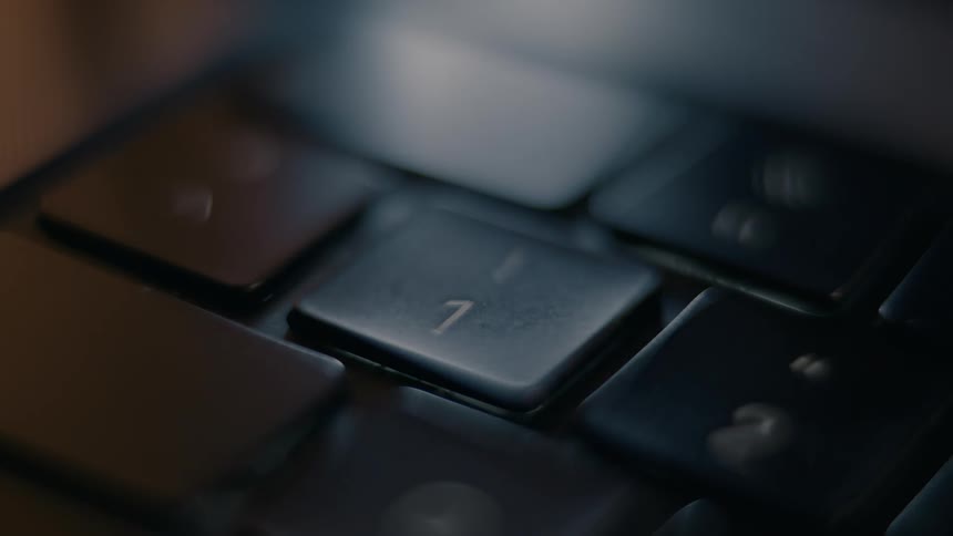 Close up of a finger pressing a single key on a laptop keyboard