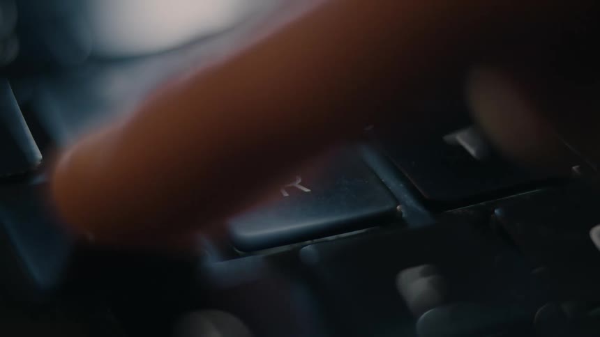 Finger clicking the letter r on a laptop