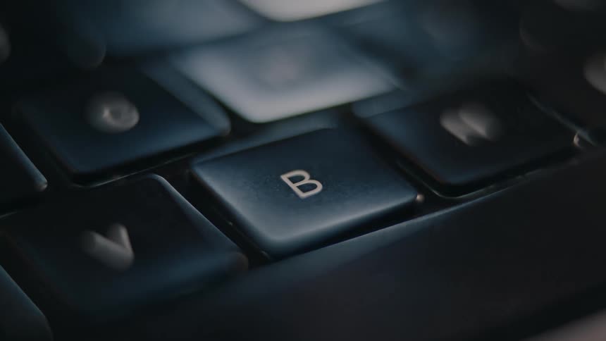 A finger pressing the b key on a keyboard